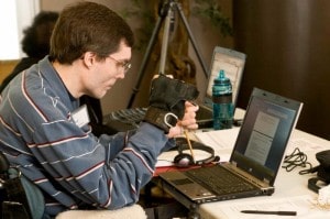 WeCo Accessibility Specialist, Chad Koch, using his wrist guard and pointer stick on his lap top computer keyboard.